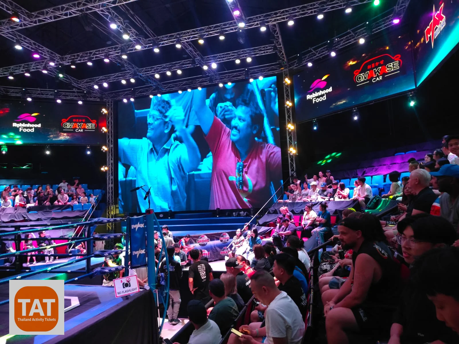 Tourists watching a Muay Thai fight from ringside stadium seating